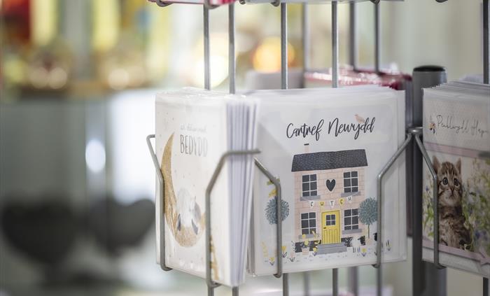 Display stand of colourful Welsh-language greeting cards and local gift cards inside the tourist information shop.